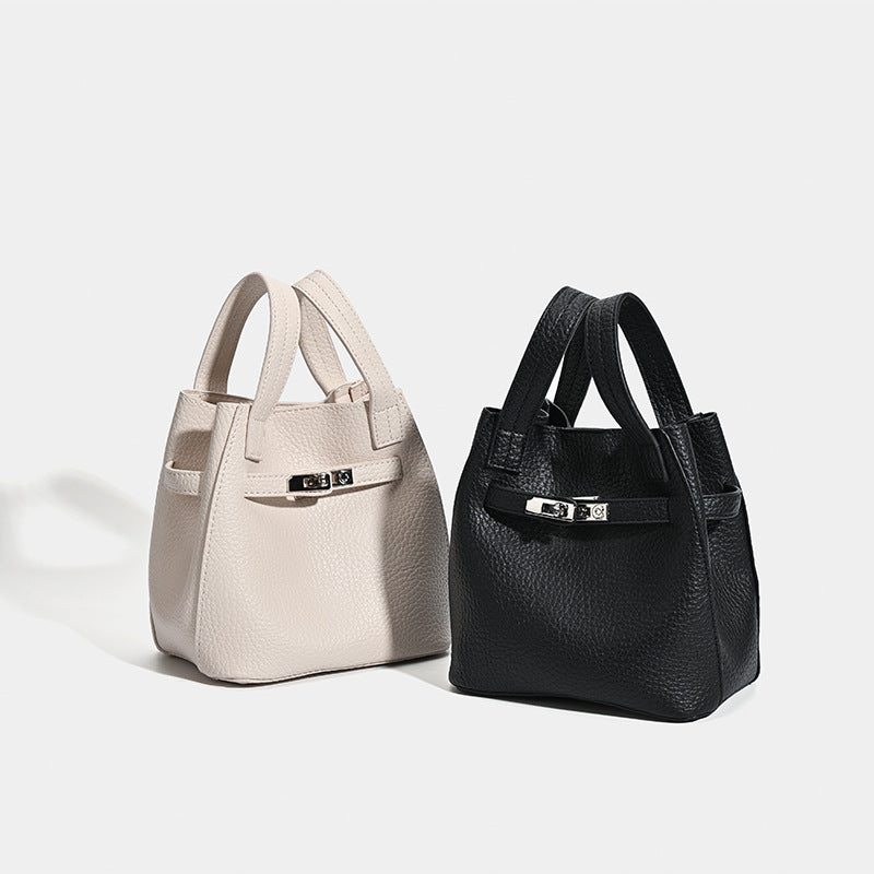 Small structured pebbled leather-look bucket bag with silver turn-lock bar hardware and dual top handles, detail view 2