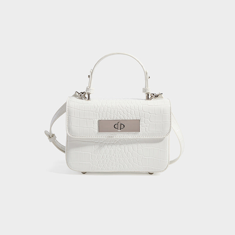 Small structured rectangular satchel with glossy crocodile-embossed finish, arched top handle, front flap, and silver-tone