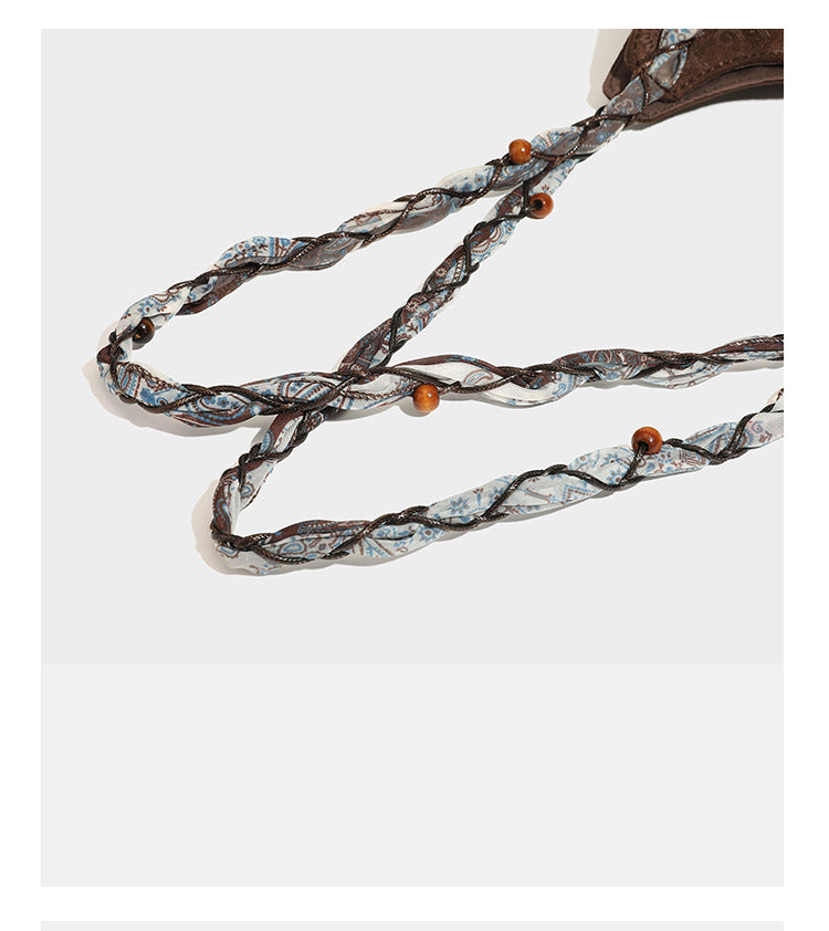Slouchy paisley-embossed suede-look shoulder tote bag with braided patterned fabric straps and wood bead accents, detail view