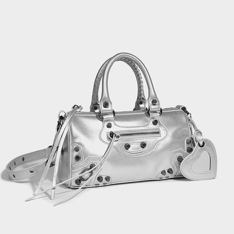 Glossy studded mini satchel bag with braided top handles, front zip pocket, heart charm, and detachable crossbody strap