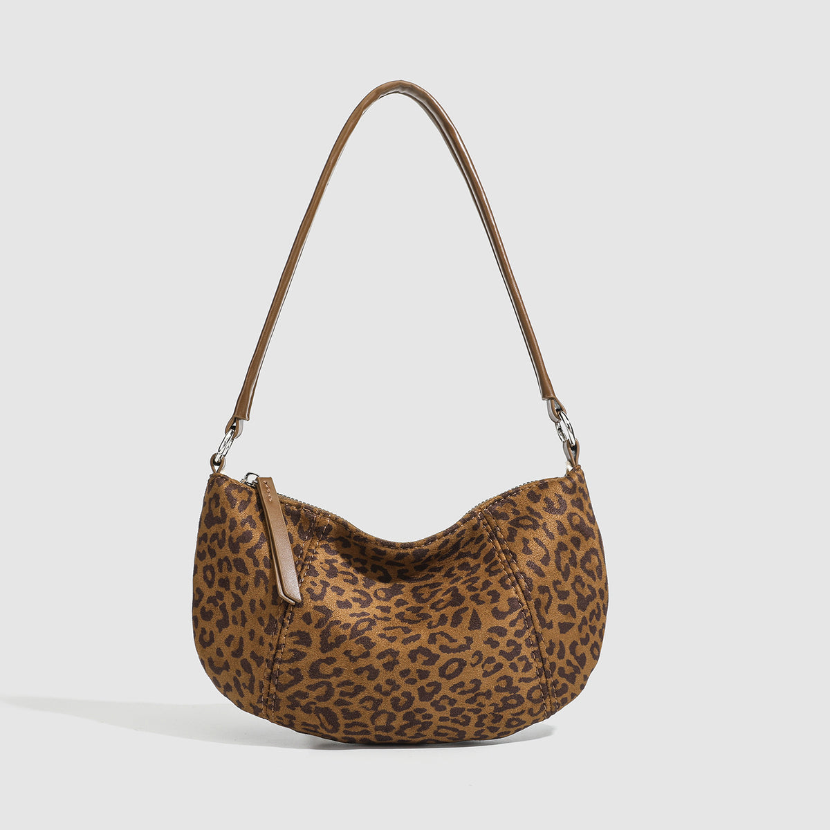 Brown and tan leopard print crescent hobo shoulder bag with zip top closure, front zip pocket, and adjustable silver-tone