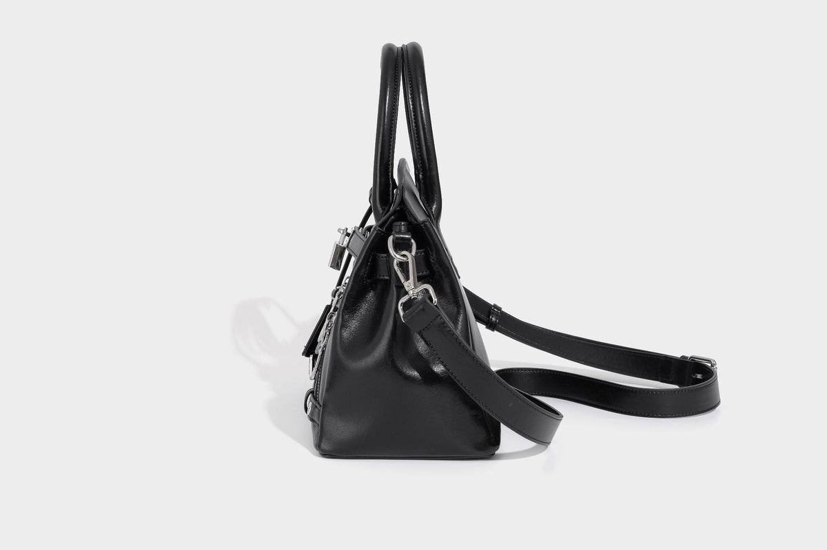 Structured black leather-look satchel bag with silver padlock hardware, front zip pockets, key charms, and top handles