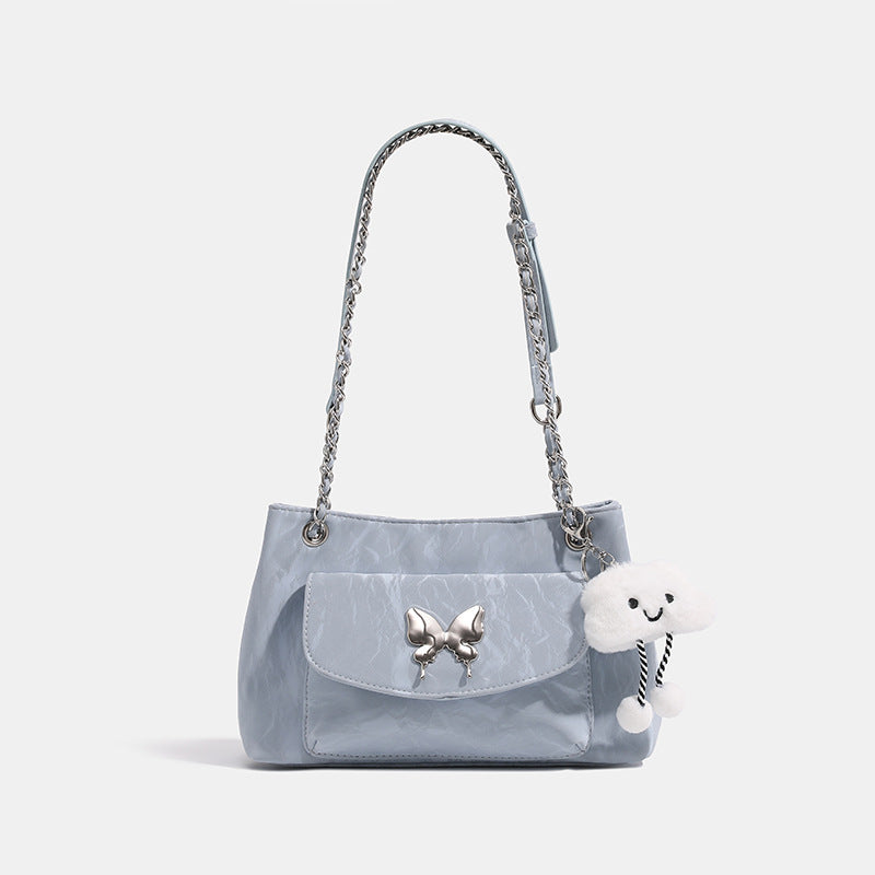 Soft rectangular glossy leather-look shoulder bag with silver chain strap, butterfly ornament on front flap pocket, and