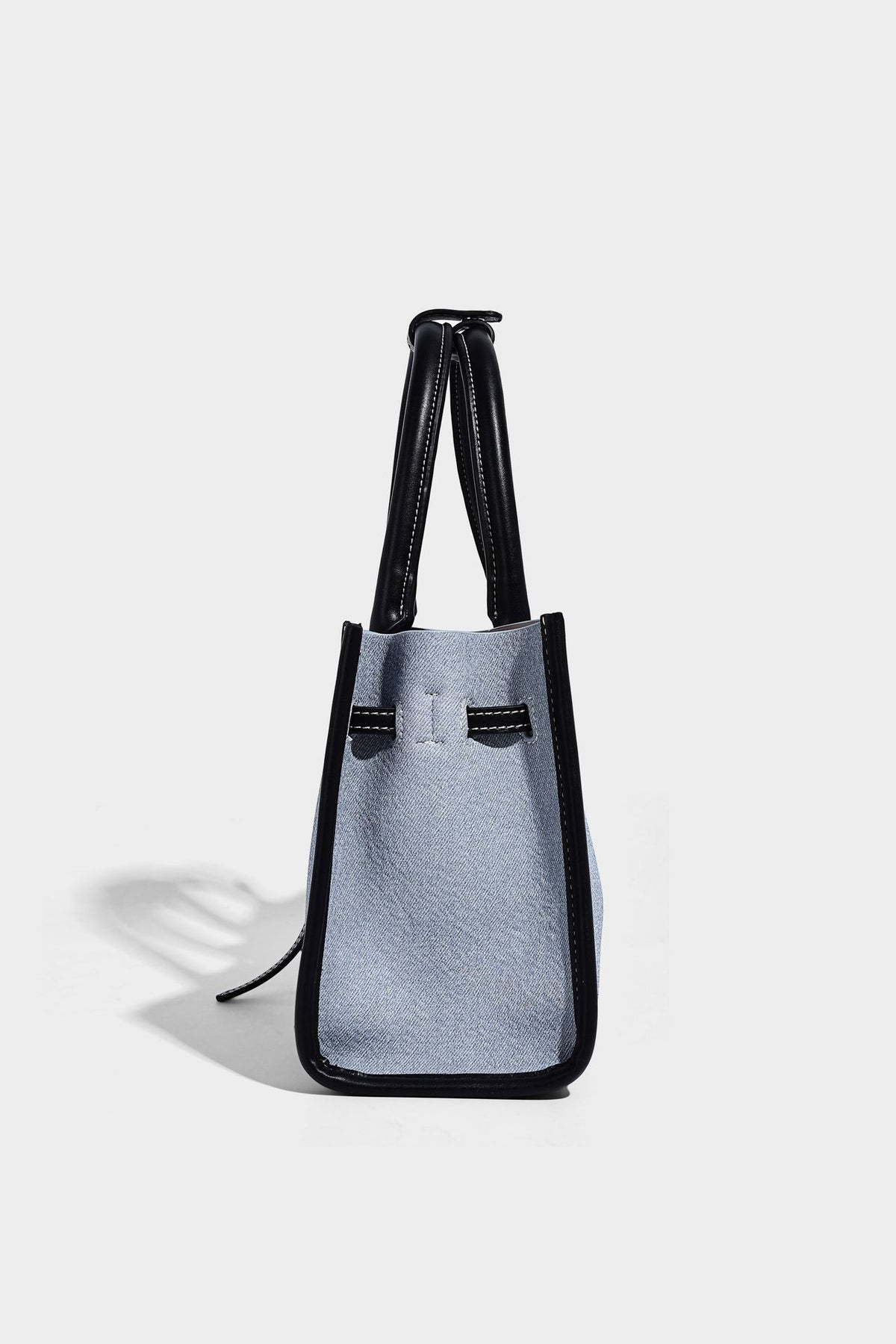 Structured rectangular tote satchel in denim-look fabric with dark trim, knotted front strap hardware, and detachable, detail