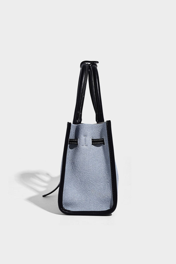 Structured rectangular tote satchel in denim-look fabric with dark trim, knotted front strap hardware, and detachable, detail
