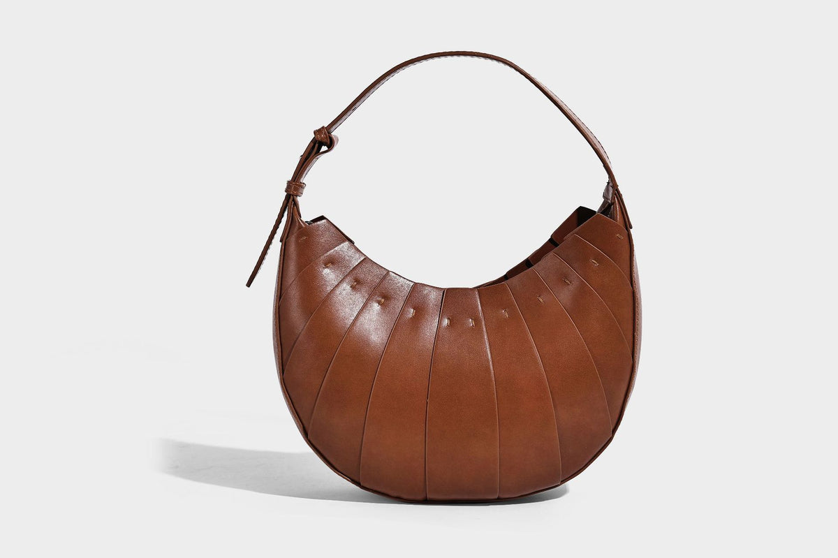 Crescent half-moon shoulder bag with vertical panel seaming, matte-satin leather-look finish, and adjustable gold-tone