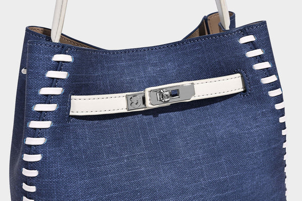 Formstabile Beuteltasche aus Denim mit weißem Zierstich-Besatz, silberfarbenem Drehverschluss, kurzen Henkeln und einem langen verstellbaren