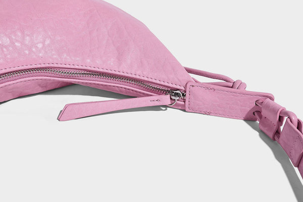 Slouchy crescent half-moon shoulder bag in pink pebbled textured finish with floral charm and knotted side detail, detail