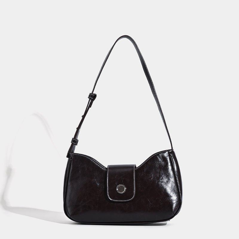Compact glossy leather-look shoulder bag with round metal snap closure and contrast stitching, front view