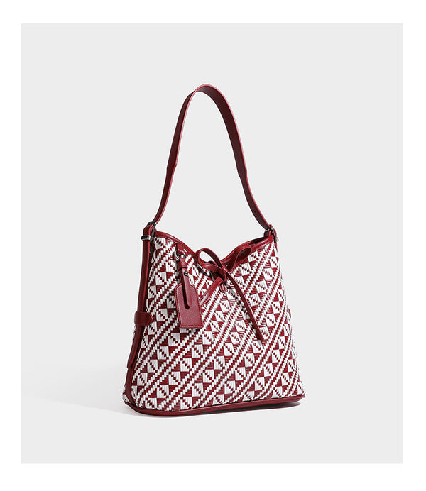 Woven geometric bucket shoulder bag in white and dark brown two-tone pattern with leather-look trim and drawstring top