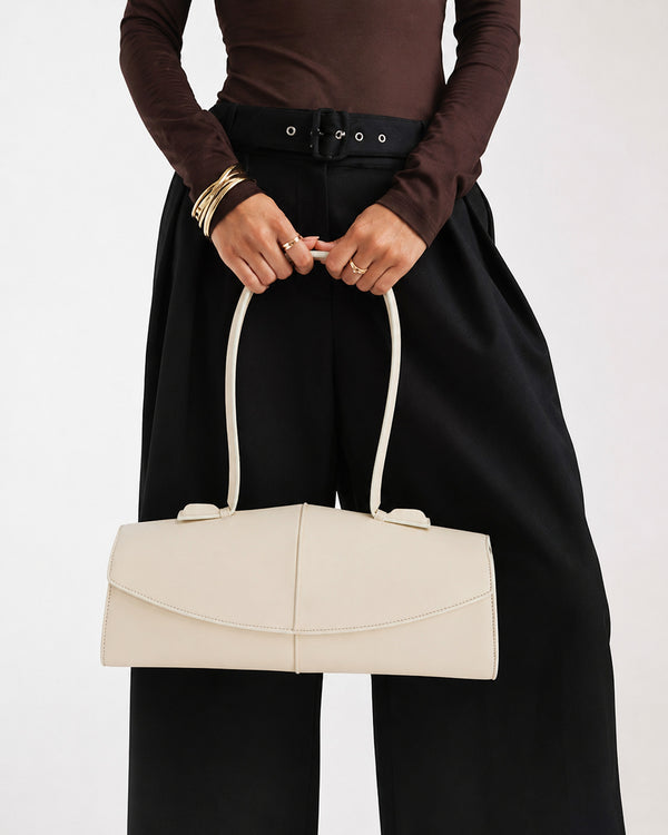 Elongated structured baguette shoulder bag with curved flap closure and slim looped strap, detail view 10