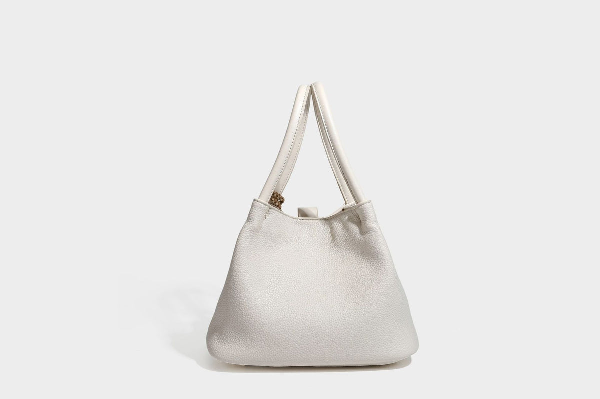 Pebbled leather-look bucket tote bag with rolled double handles, drawstring closure, braided cord charm, and detachable