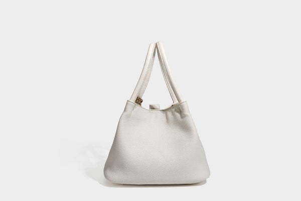 Pebbled leather-look bucket tote bag with rolled double handles, drawstring closure, braided cord charm, and detachable
