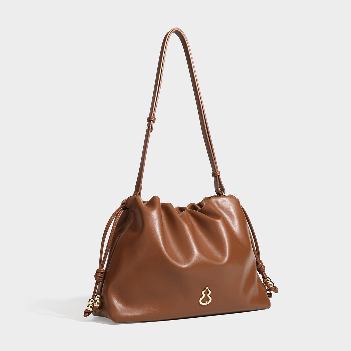 Slouchy ruched drawstring shoulder bag in smooth leather-look finish with gold-tone emblem and slim adjustable strap, front