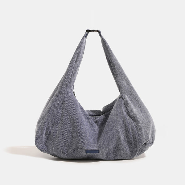 Oversized slouchy black textured canvas hobo shoulder bag with zip-top closure and adjustable dark-hardware strap, detail