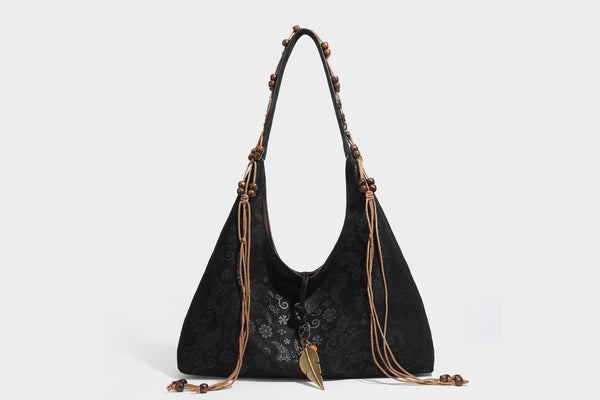Slouchy boho hobo shoulder bag in embossed brown suede-look finish with beaded strap, cord tassels, and brass-tone leaf