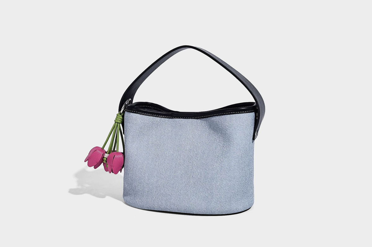 Hellblaue Bucket-Bag aus Denim mit schwarzem Besatz in Lederoptik, silberfarbenen Beschlägen, kurzem Tragegriff und langem verstellbarem Crossbody-Riemen