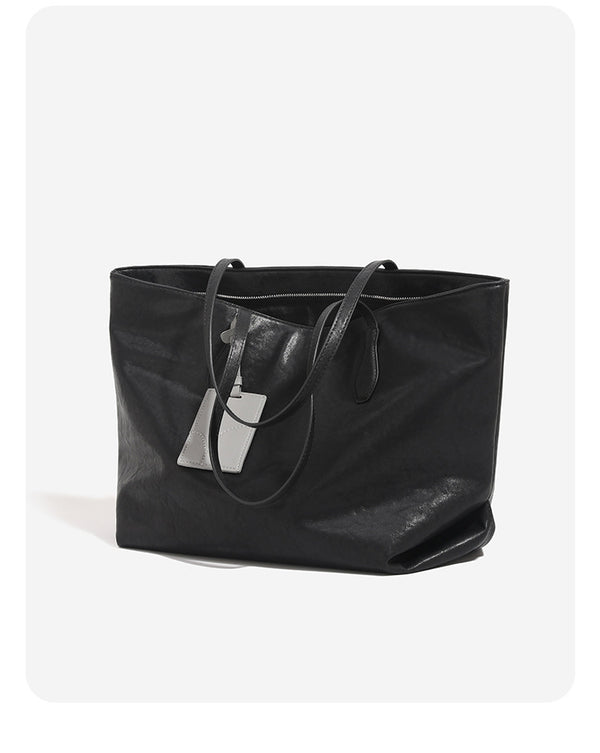 Oversized slouchy leather-look tote bag with long shoulder straps, contrast grey hanging tag, and silver-tone hardware