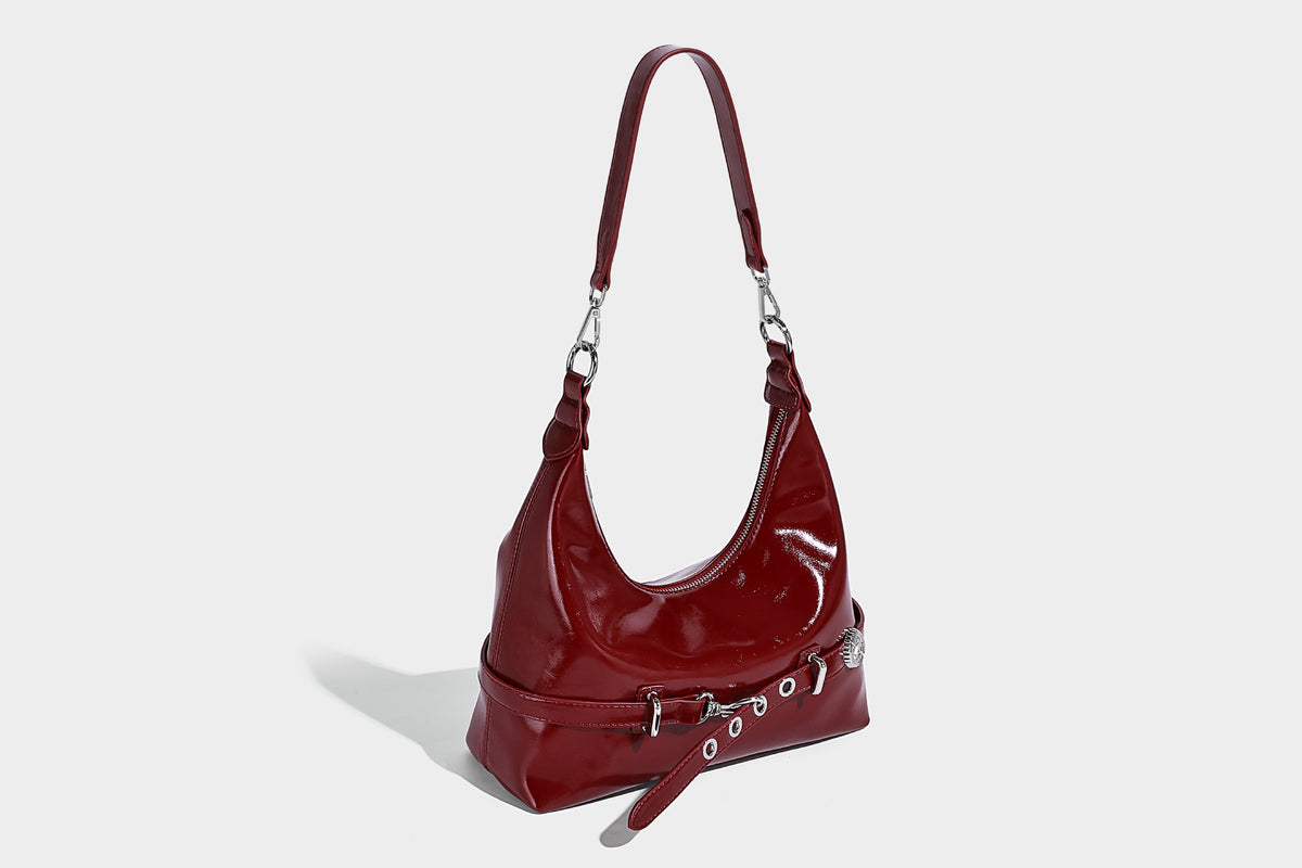 Glossy black slouchy hobo shoulder bag with silver-tone hardware, belt-style grommet strap at base, and long adjustable