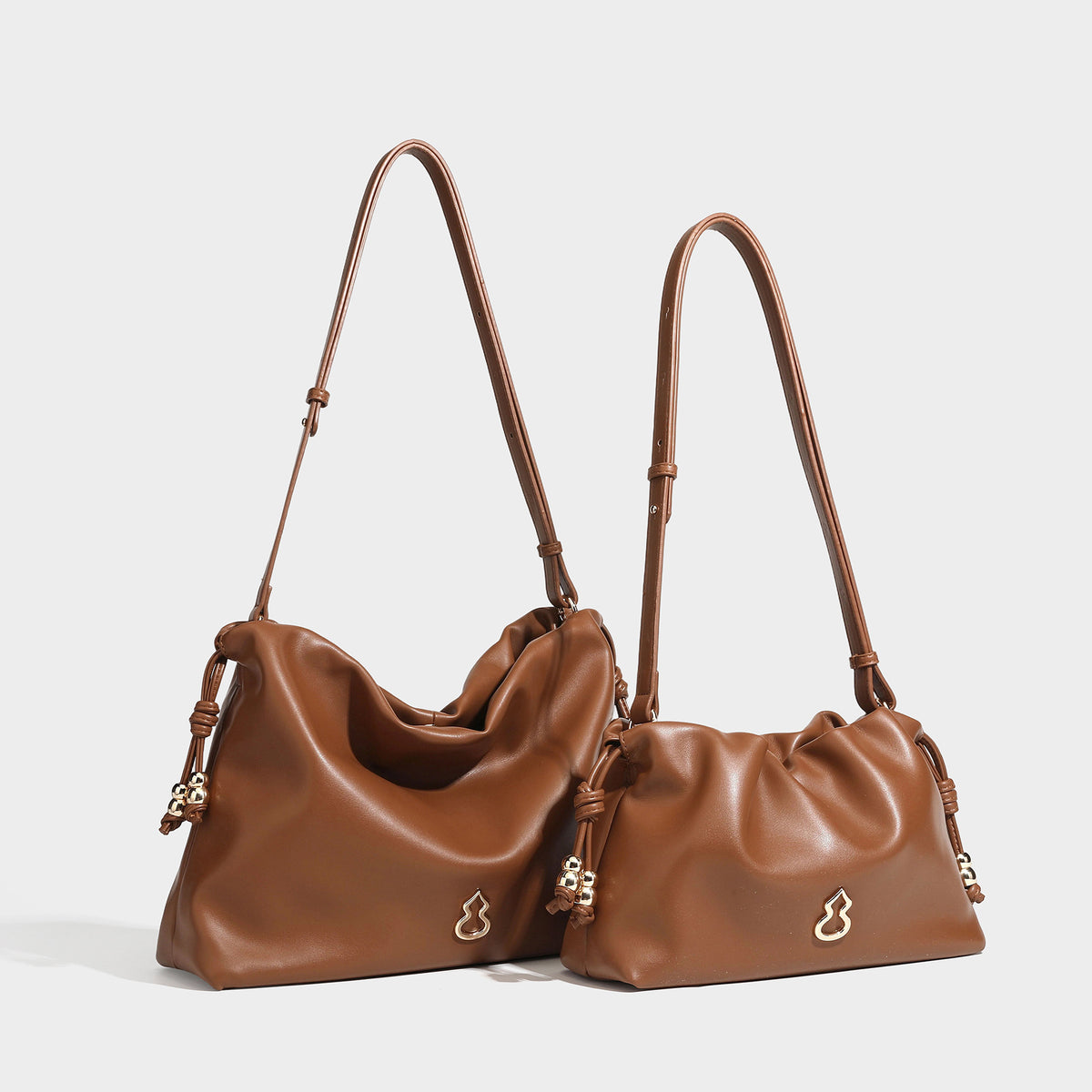 Slouchy ruched drawstring shoulder bag in smooth leather-look finish with gold-tone emblem and slim adjustable strap, detail