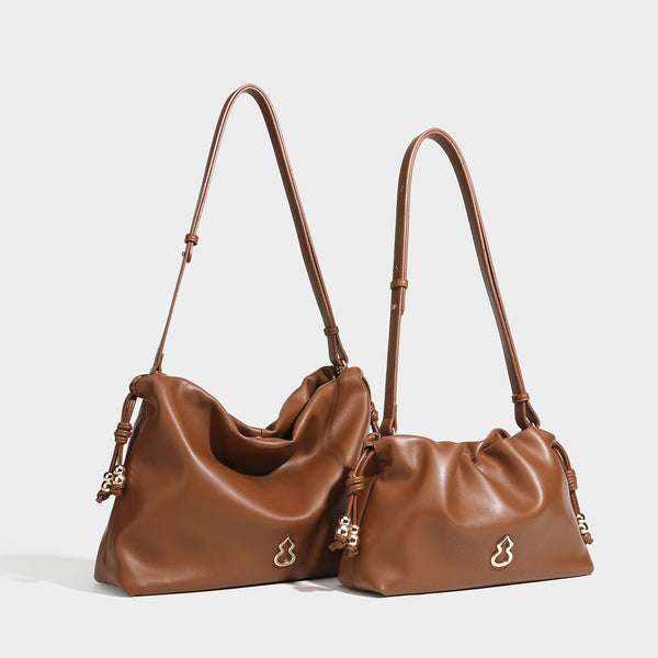 Slouchy ruched drawstring shoulder bag in smooth leather-look finish with gold-tone emblem and slim adjustable strap, detail
