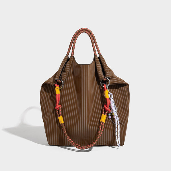 Slouchy pinstripe tote bag with braided rope handles, metal ring hardware, and colorful knotted rope charm, detail view 11