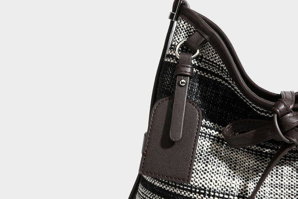 Schwarz-weiß karierte Hobo-Schultertasche aus gewebtem Material mit dunkelbrauner Einfassung in Lederoptik, Kordelzugverschluss und langem, verstellbarem