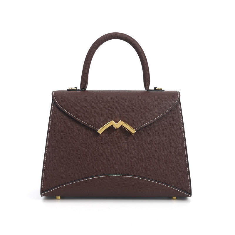 Structured trapezoid top-handle satchel in golden brown cross-grain textured finish with gold M-shaped clasp hardware and