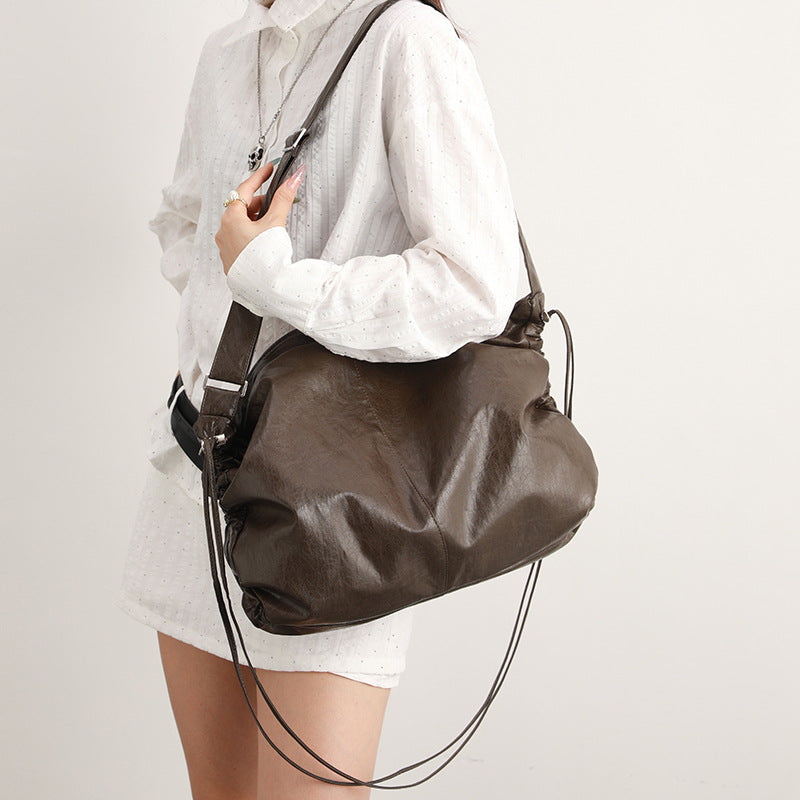 Oversized slouchy hobo shoulder bag with glossy crinkled leather-look finish, drawstring gathered sides, and silver-tone