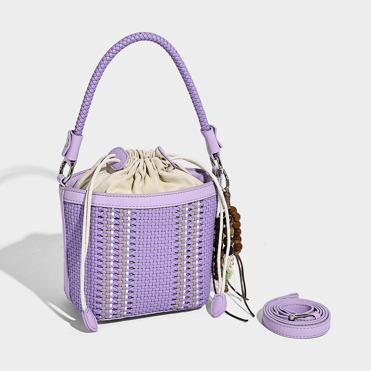 Small woven bucket bag with drawstring top, braided handle, detachable crossbody strap, and silver-tone ring hardware, detail
