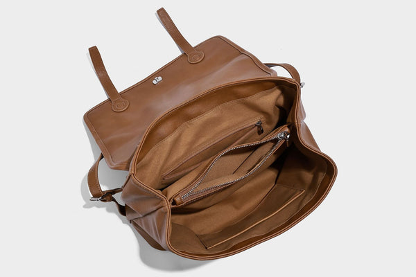 Structured tan leather-look flap backpack handbag with top handle, silver buckle hardware, and fold-over front closure