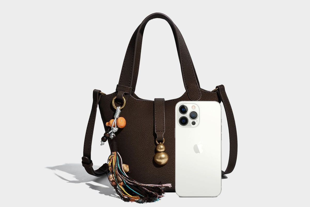 Kleine matte Beuteltasche mit genarbter Oberfläche, antikgoldfarbenen Ringbeschlägen, Perlen- und Quastenanhänger, kurzen Tragegriffen oben und