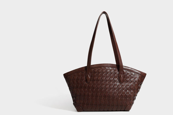 Large leather-look tote bag with geometric woven emboss, double shoulder straps, and round woven cord charm in brown, detail