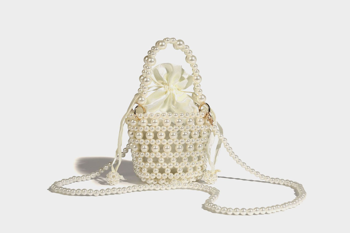 Elfenbeinfarbene Mini-Bucket-Bag aus Kunstperlen mit Satin-Innenbereich und Zugband, goldfarbenen Ringbeschlägen und gewölbtem Perlenhenkel an der Oberseite