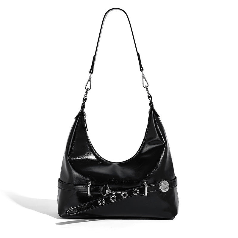 Glossy black slouchy hobo shoulder bag with silver-tone hardware, belt-style grommet strap at base, and long adjustable