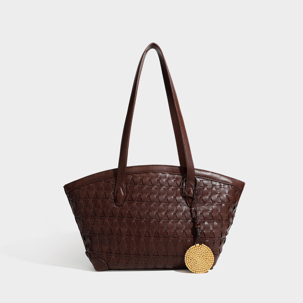 Large leather-look tote bag with geometric woven emboss, double shoulder straps, and round woven cord charm in brown, detail