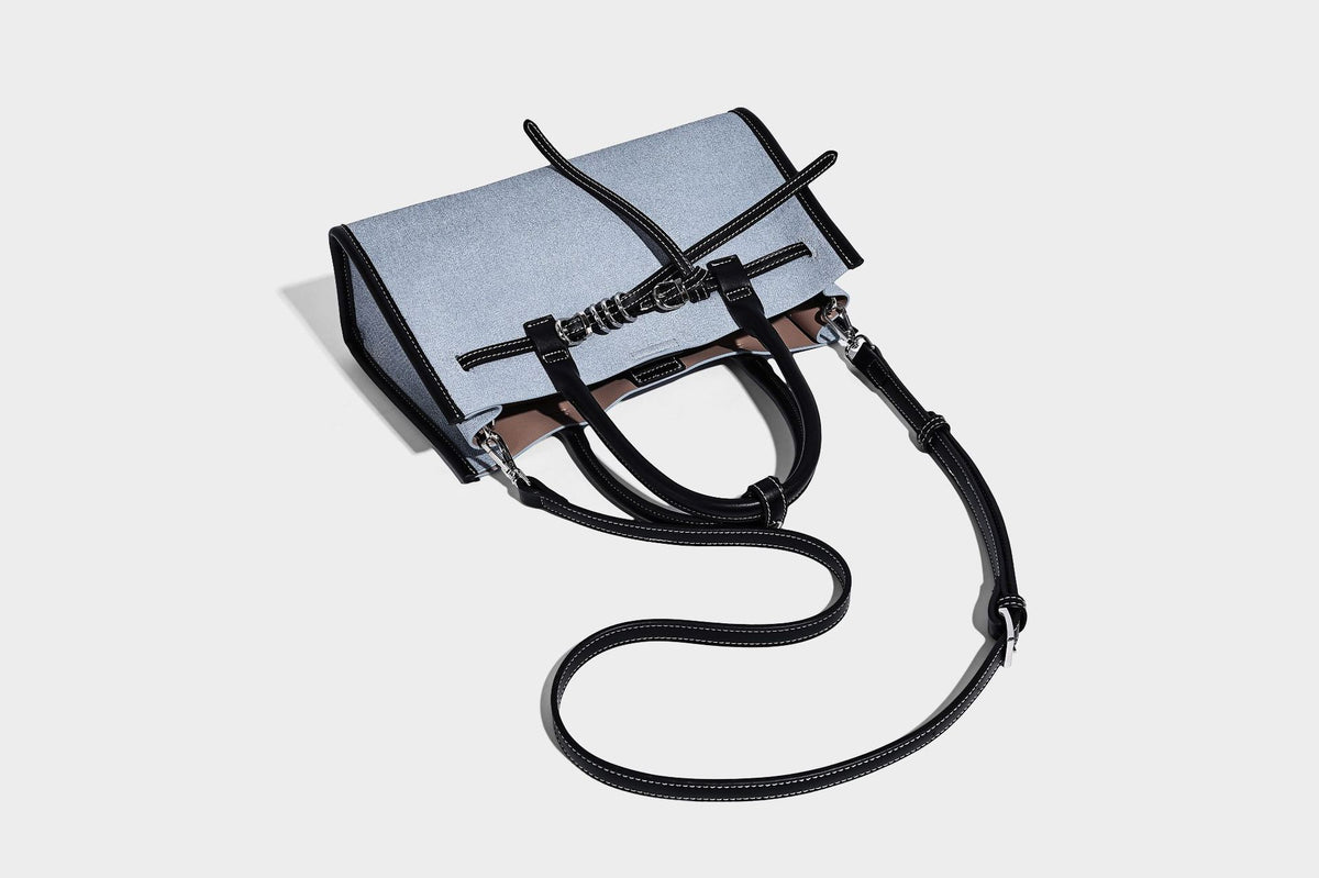 Structured rectangular tote satchel in denim-look fabric with dark trim, knotted front strap hardware, and detachable, detail