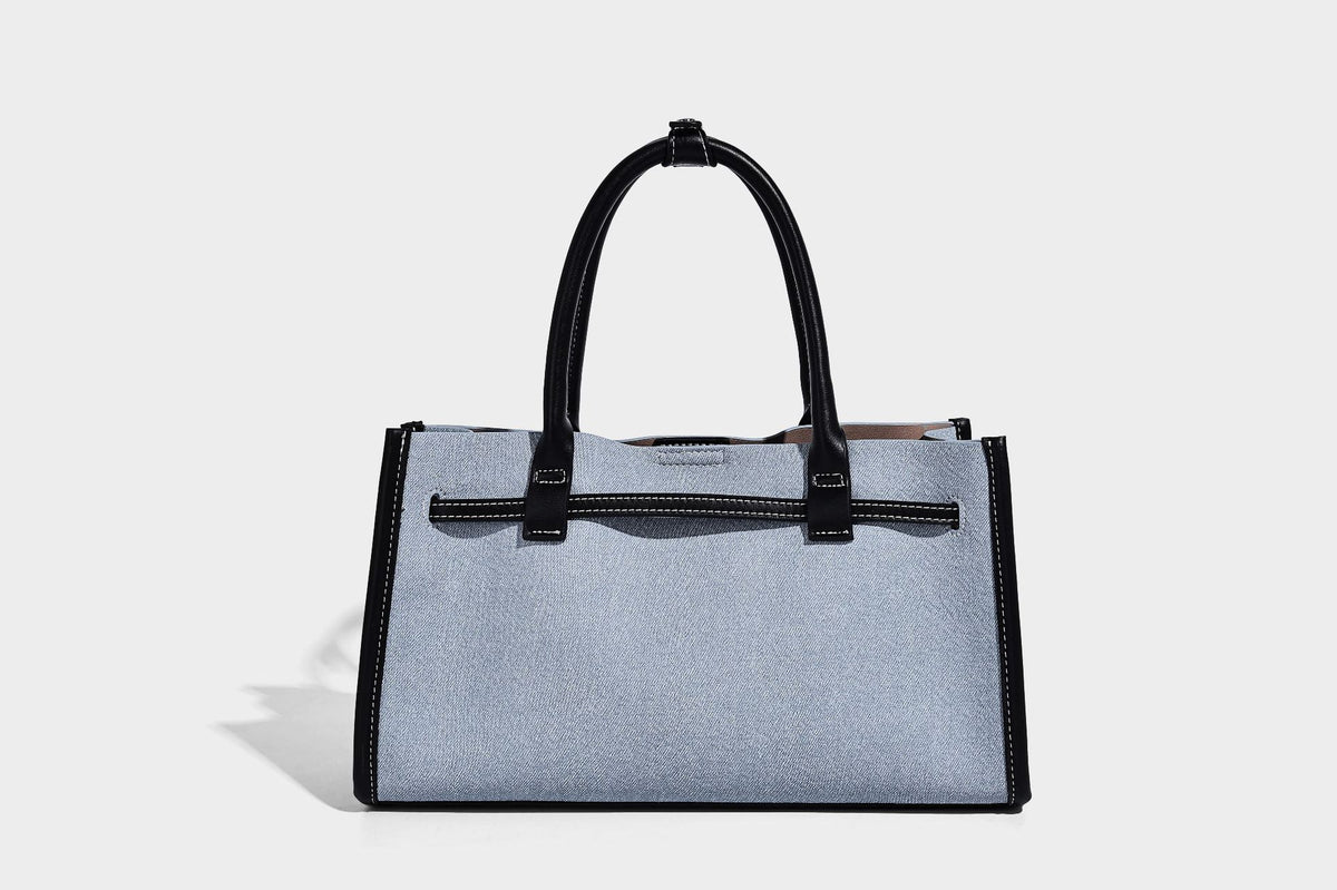 Structured rectangular tote satchel in denim-look fabric with dark trim, knotted front strap hardware, and detachable, detail