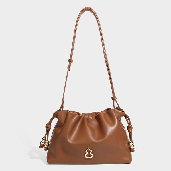 Slouchy ruched drawstring shoulder bag in smooth leather-look finish with gold-tone emblem and slim adjustable strap, detail