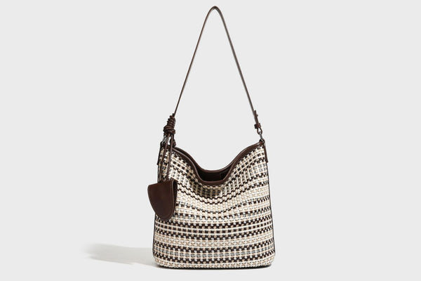 Woven stripe bucket shoulder bag in cream and dark brown with leather-look trim, knotted adjustable strap, and small shield