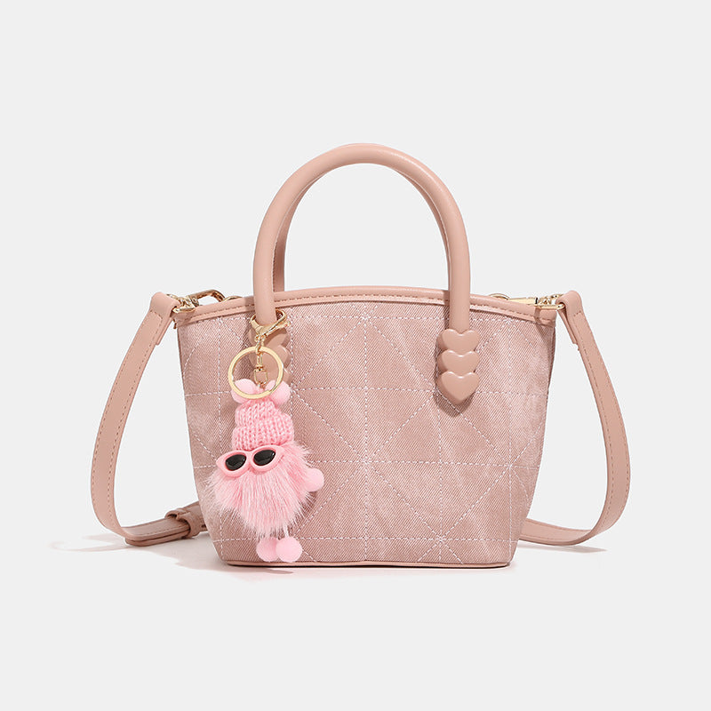 Quilted leather-look mini bucket tote bag with heart-shaped side accents, gold-tone hardware, fuzzy character charm, and