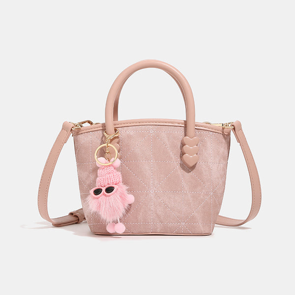 Quilted leather-look mini bucket tote bag with heart-shaped side accents, gold-tone hardware, fuzzy character charm, and