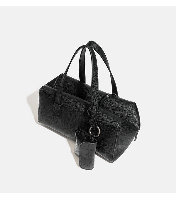Structured pebbled leather-look top-zip barrel bag with dual handles, detachable shoulder strap, and attached croc-pattern