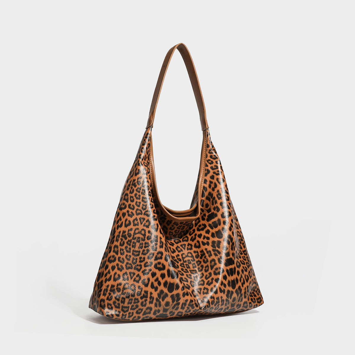 Glossy leopard-print slouchy shoulder bag with long strap and detachable tan zip pouch, front view
