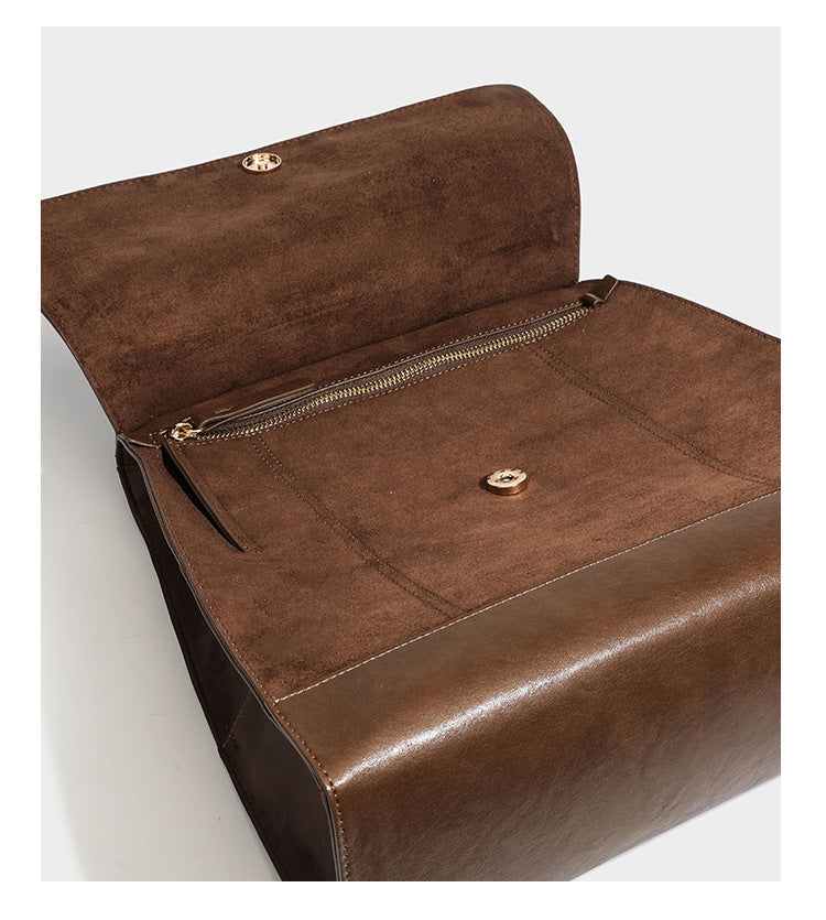Structured suede-look convertible backpack handbag with flap closure and gold-tone emblem hardware in chocolate brown, detail