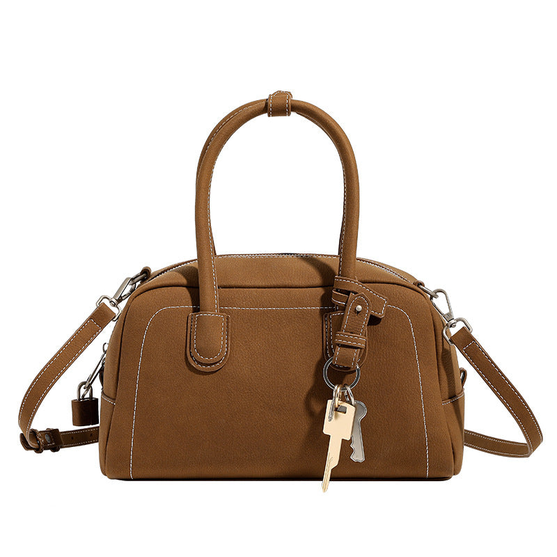 Kompakte, strukturierte Henkeltasche mit matter genarbter Oberfläche, geknoteten Doppelgriffen, goldenem Schlüsselanhänger und abnehmbarem, Detailansicht