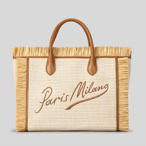 Naturfarbene, elfenbeinfarbene Strohtasche mit gewebter Optik, Bastfransenbesatz, cognacfarbenen Henkeln in Lederoptik und aufgesticktem Schriftzug „Paris Milano“