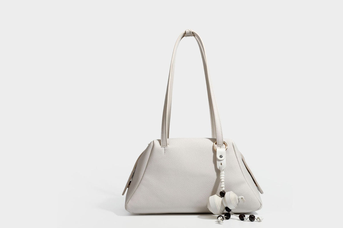 Structured trapezoid shoulder bag in dark brown pebbled leather-look finish with slim double straps, top zip closure, side
