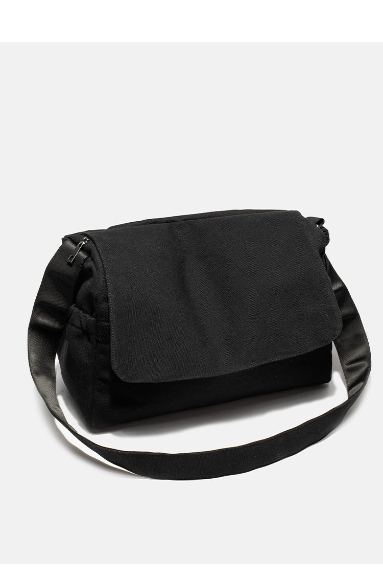 Große schwarze Messenger-Tasche aus mattem Canvas mit Überschlag vorn, Reißverschluss oben, elastischen Seitentaschen und verstellbarem silberfarbenem
