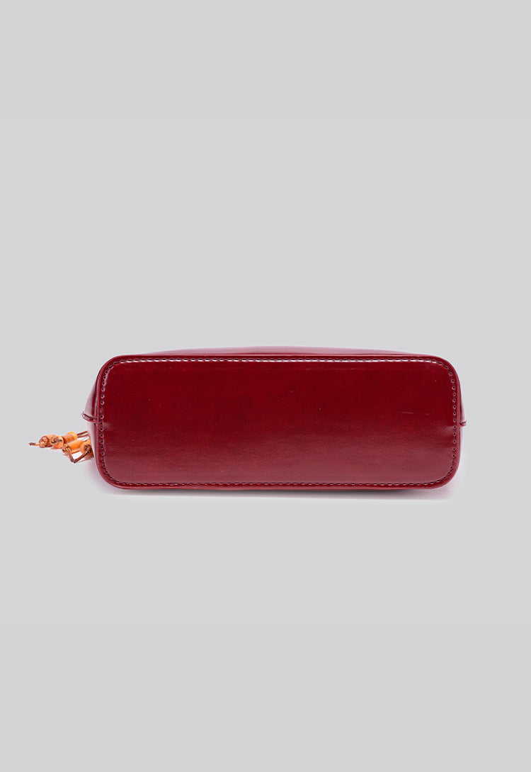 Glossy crescent hobo shoulder bag in deep burgundy with beaded wood tassel charm and gold-tone ring hardware, detail view 11